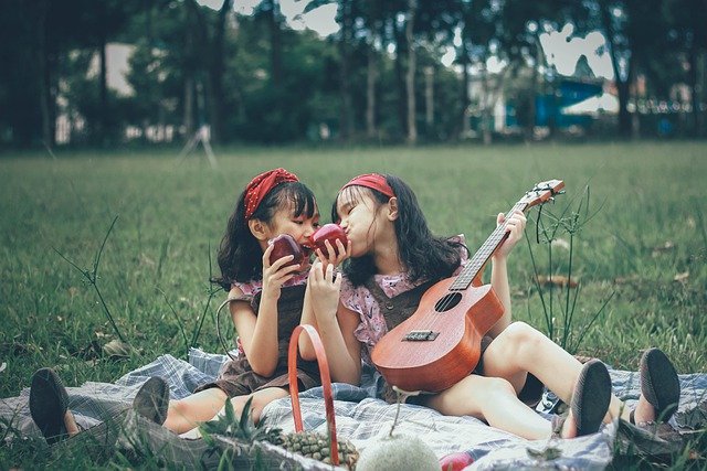 Duas crianças fazendo piquenique e tocando ukelele.